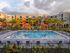 Stylish apartment complex with a pristine swimming pool surrounded by lush palm trees and vibrant lounge areas.