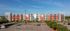 Modern multistory apartment building with dynamic red and gray facade and spacious parking area.