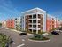 Modern four-story apartment complex with colorful facades and ample parking.