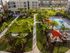 Aerial view of a luxurious apartment complex with landscaped gardens, palm trees, and a sparkling swimming pool.