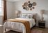 Inviting bedroom with neutral tones, featuring a plush bed, cozy throw, and artistic wall decor.