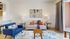 Bright and modern living room featuring a cozy gray sofa, vibrant blue armchair, and decorative wall art.