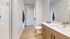 Modern bathroom with sleek wooden cabinets and a large mirror, featuring a walk-in shower.