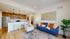 Bright and stylish open living room with modern kitchen, featuring a cozy blue sofa and elegant decor.
