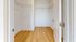 Walk-in closet with wooden flooring and white shelving.