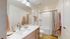 Modern bathroom featuring a sleek vanity with dual sinks, large mirror, and bright lighting.