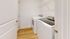 Bright laundry room with a top-loading washer and front-loading dryer, featuring a sleek design and wooden flooring.