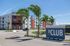 Contemporary apartment complex with palm trees and modern architecture on a sunny day.