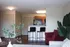 Inviting living space featuring a cozy open kitchen with bar seating, lush greenery, and a comfortable red armchair.