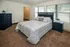 Inviting bedroom with plush carpet, elegant blue furniture, and large windows offering natural light.