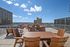 Breathtaking rooftop terrace with modern seating, offering stunning city skyline views under a clear blue sky.