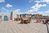 Expansive rooftop deck with stylish seating offering stunning city views under a bright blue sky.