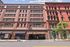 Vibrant urban apartment building with charming red brick facade, showcasing mixed-use spaces and convenient parking access.