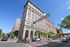 Stunning view of a historic downtown building under a clear blue sky, showcasing vibrant city life with pedestrians and cars. Perfect location near popular farmers market.