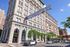 Charming historic building in downtown with leasing opportunities, adjacent to vibrant farmers market banner under a bright blue sky.