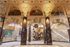 Historic architectural elegance showcased in a grand entrance lobby with intricate murals, marble columns, and an ornate ceiling.