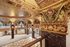 Exquisite grand hall featuring ornate golden columns, intricate ceiling designs, and expansive windows in a luxurious setting.