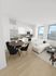 Modern open-plan living space with sleek white kitchen, stylish dining area, and cozy living room featuring a plush sofa and coffee table, complemented by expansive windows offering stunning city views.