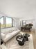 Bright, modern living area with large arch windows, sleek kitchen, and elegant decor, perfect for urban living.