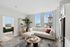 Sophisticated living area in modern apartment, featuring a plush white sofa, elegant wooden coffee table, and stunning city views through large windows.