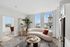 Bright modern living area with a cozy curved sofa, stylish decor, and large windows showcasing a stunning cityscape view.