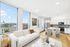 Bright modern apartment with an open-concept living and kitchen area, featuring stylish furnishings and expansive city views through large windows.