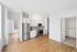 Bright and modern kitchen with stainless steel appliances, hardwood floors, and ample cabinetry in a sleek apartment layout.