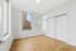 Bright and airy bedroom with sleek hardwood floors, modern white walls, and large windows showcasing a stunning city view.