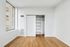 Bright bedroom with sleek hardwood flooring and a spacious built-in closet, featuring a modern sliding door and ample shelving.