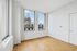 Bright, spacious room with elegant hardwood flooring and large windows showcasing a stunning cityscape view.