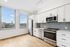 Modern kitchen with sleek stainless steel appliances, elegant white cabinetry, and large windows offering a beautiful urban view.
