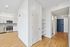 Contemporary apartment kitchen with sleek stainless steel appliances, pristine white cabinetry, and elegant hardwood flooring, offering a bright and modern living space.