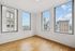 Bright apartment corner room with wide cityscape views through large windows and elegant hardwood floors.
