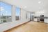Bright and modern apartment with an open floor plan, featuring a sleek kitchen with stainless steel appliances and large windows offering stunning city views.