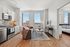 Modern urban apartment with an open-concept living room and kitchen, showcasing elegant hardwood floors and panoramic city views.