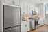 Sleek modern kitchen with stainless steel appliances, elegant white cabinetry, and stylish subway tile backsplash, illuminated by natural light from a large window.