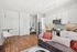 Chic open-concept apartment showcasing a modern kitchen with sleek cabinetry, cozy office nook, and stylish living area featuring plush seating and contemporary decor.