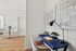 Chic and inviting home office with blue desk, elegant vintage telephone, and stylish wall art; adjacent to a modern dining area with plush chairs.