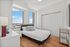 Bright and airy bedroom with panoramic city views, featuring a cozy bed and elegant decor.