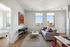 Charming apartment living room with elegant modern decor, a plush sofa, vibrant art piece, and stunning cityscape views through large windows.