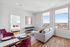 Bright city apartment with a cozy living room, elegant dining area with vibrant pink chairs, and a spacious bedroom with large windows overlooking the cityscape.