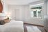 Bright and cozy bedroom with modern decor, featuring a plush bed, stylish lamp, and a large window offering a scenic view.