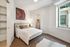 Bright and inviting bedroom with elegant decor, cozy bedding, and ample natural light through a large window, featuring a spacious walk-in closet.
