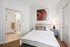 Elegant bedroom with modern decor, plush bedding, and an en-suite bathroom featuring a glass shower.