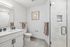 Elegant bathroom featuring a sleek vanity with double sinks, modern shower with glass doors, and stylish wall art.