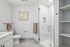 Elegant bathroom design featuring a modern glass-enclosed shower, sleek white vanity, and tasteful wall art, perfect for a serene retreat.
