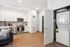 Modern apartment interior showcasing a sleek kitchen with stainless steel appliances, bright cabinets, and wooden floors, complemented by an in-unit washer and dryer.
