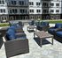 Spacious and stylish apartment patio featuring elegant wicker seating with plush blue cushions, surrounded by a well-maintained outdoor area.