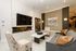 Elegant living room with a sleek modern fireplace, large wall-mounted TV, and plush seating. Stylish decor includes a marble coffee table and sophisticated lighting fixtures.