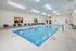 Elegant indoor pool area with modern seating, bright lighting, and sleek tile flooring, perfect for relaxation and leisure.